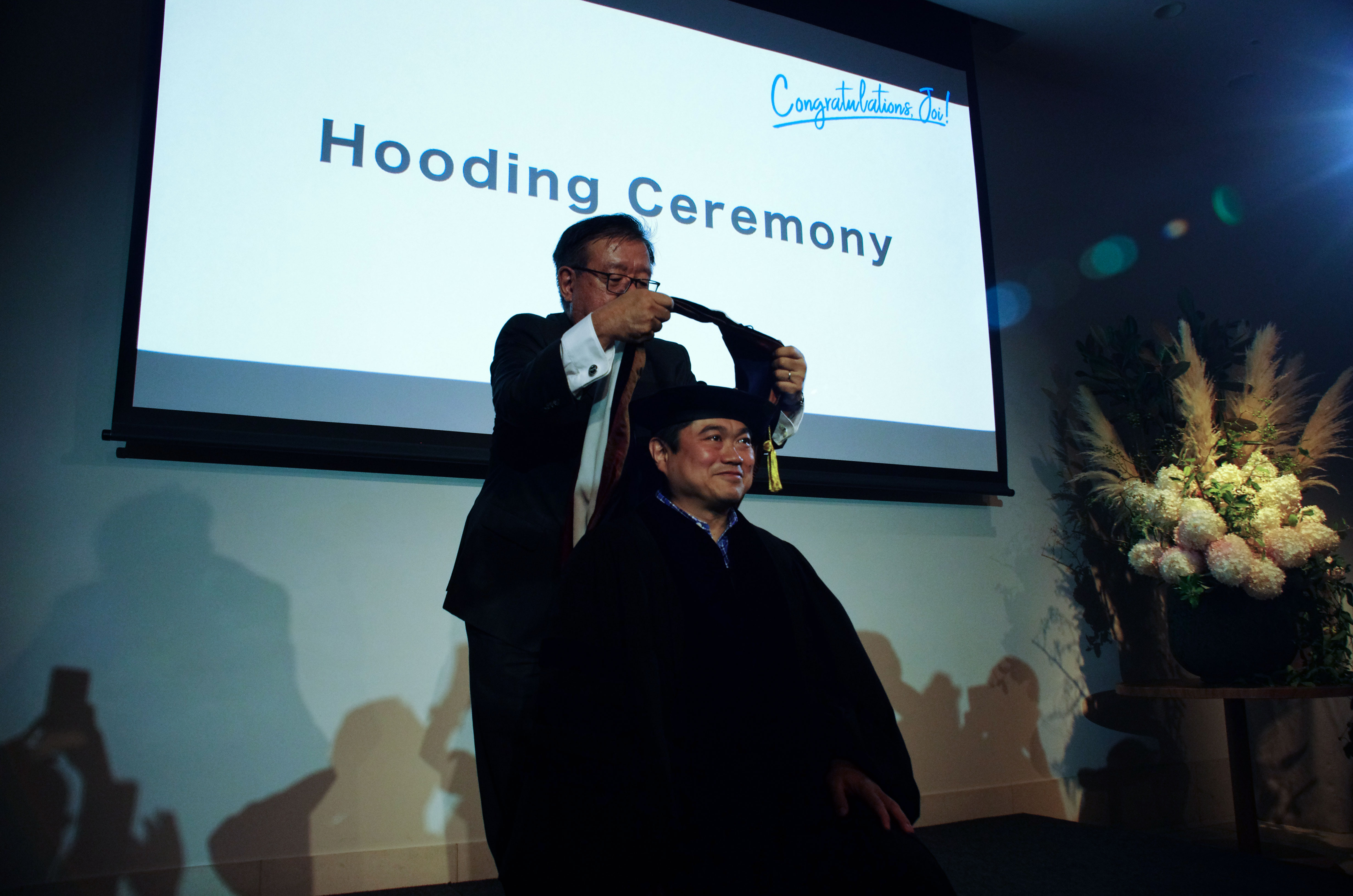Hooding Ceremonyで博士号の証のマントを村井教授から授与されるJoi