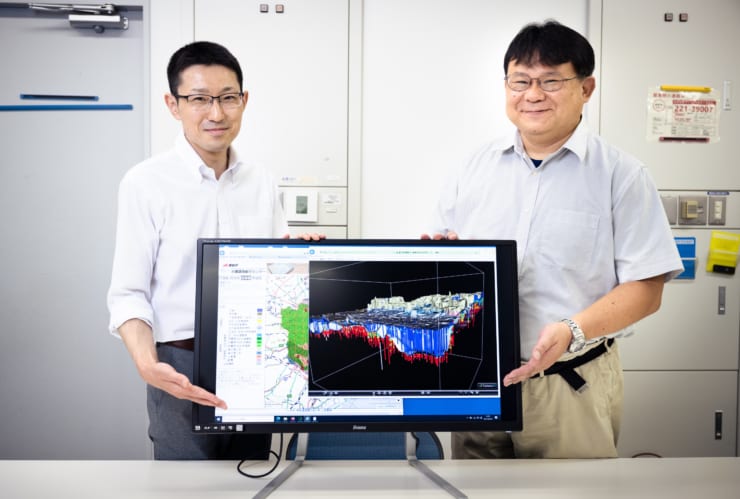 「3次元地質地盤図〜東京23区版〜」の画面を指し示す産総研 地質調査総合センター 地質情報研究部門 情報地質研究グループの中澤努氏（右）と野々垣進氏（左）