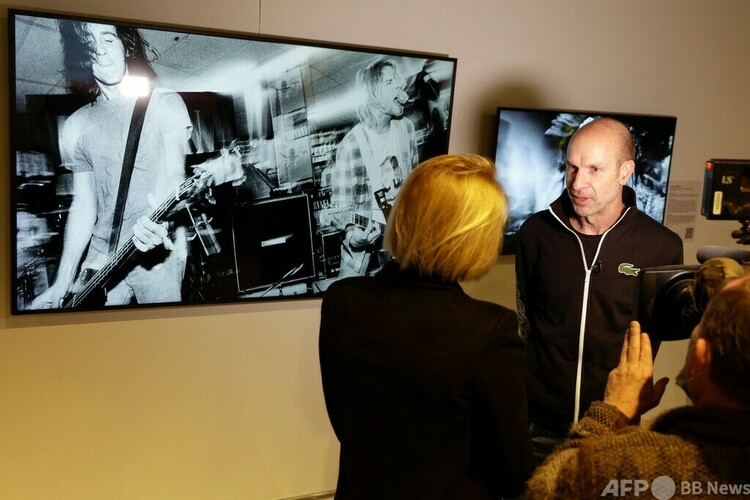 米ワシントン州にオープンした「シアトルNFTミュージアム」で、バンド「ニルヴァーナ」の公演の様子を撮影した作品の前で取材に応じる写真家のチャールズ・ピーターソン氏（2022年1月29日撮影）。(c)Jason Redmond / AFP