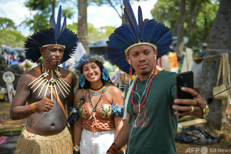 ブラジルの首都ブラジリアの野営地で、ファンとの写真撮影に応じる先住民インフルエンサーのサメラ・アウィアさん（中央）とトゥクマ・パタショさん（右、2022年4月7日撮影）。(c)Carl de Souza / AFP