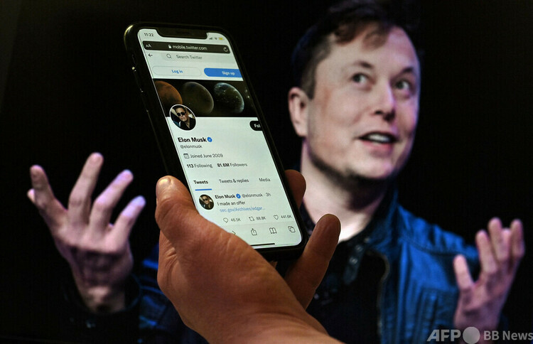 イーロン・マスク氏のツイッターアカウントを表示した携帯電話の画面（2022年4月14日撮影、資料写真）。(c)Olivier DOULIERY : AFP