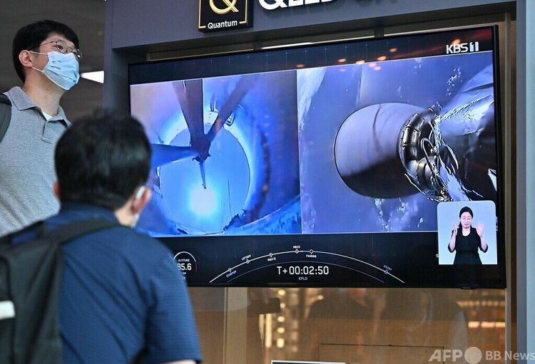 韓国初の月探査機を載せた宇宙開発企業スペースXの「ファルコン9」ロケットの打ち上げを報じるテレビ番組を見る人々。ソウルの鉄道駅にて（2022年8月5日撮影）。(c) Jung Yeon-je / AFP