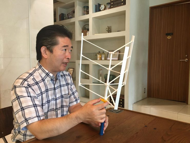 「浮遊軸型風車」の模型を示す秋元氏