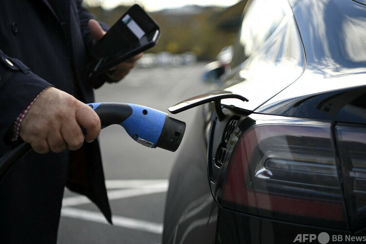 電気自動車の充電の準備をする人（2020年11月18日撮影）。(c)Daniel LEAL : AFP