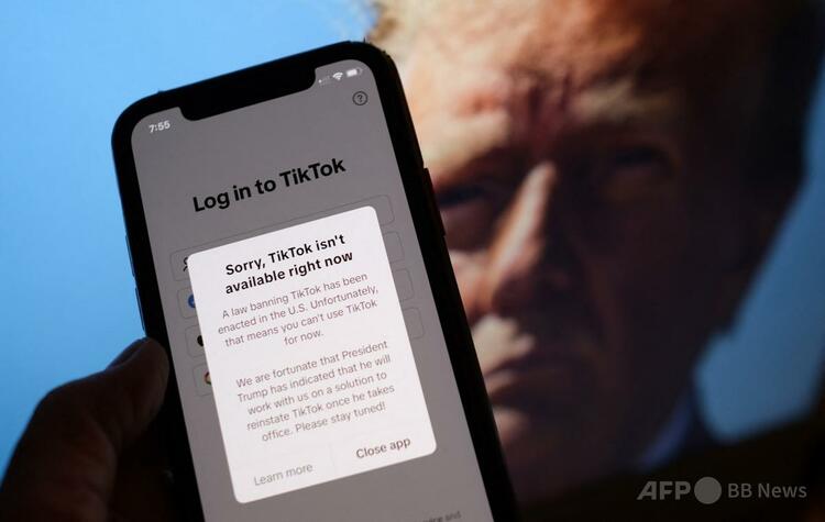 スマートフォンの画面に表示されたTikTokの米国でのサービス停止を伝えるメッセージと、ドナルド・トランプ次期米大統領の写真（2025年1月18日撮影）。（c）Chris DELMAS:AFP