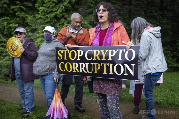 ドナルド・トランプ米大統領の関わる仮想通貨（暗号資産）「＄TRUMP」の保有者上位220人を招いたプライベートディナーの会場となった米バージニア州スターリングの「トランプ・ナショナル・ゴルフコース」の外で抗議する人々（2025年5月22日撮影）。(c)Jim WATSON/AFP