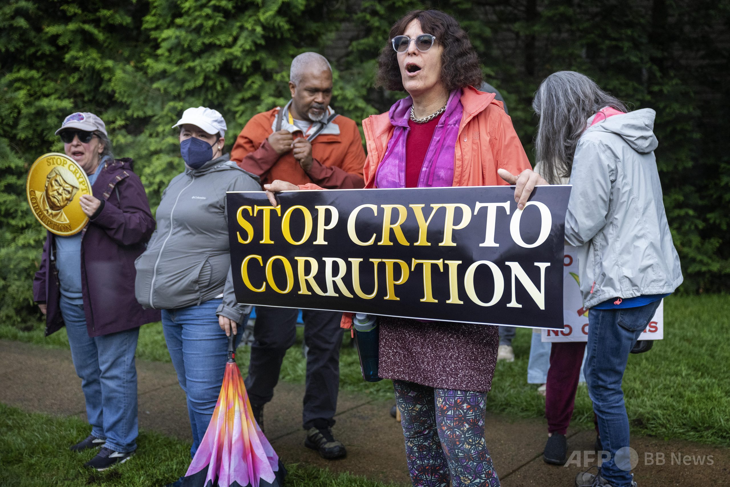 ドナルド・トランプ米大統領の関わる仮想通貨（暗号資産）「＄TRUMP」の保有者上位220人を招いたプライベートディナーの会場となった米バージニア州スターリングの「トランプ・ナショナル・ゴルフコース」の外で抗議する人々（2025年5月22日撮影）。(c)Jim WATSON/AFP