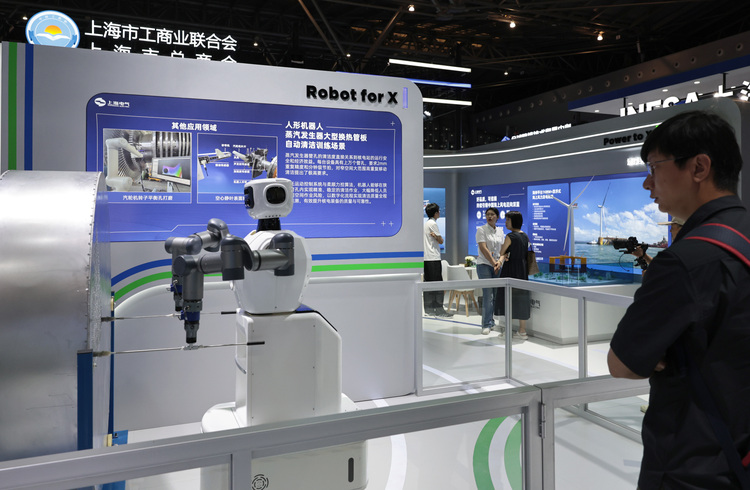 上海電気集団のブース前で、人型ロボットによる原発設備清掃の実演を見る来場者（2025年6月11日撮影）。(c)Xinhua News