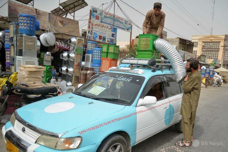 アフガニスタンのカンダハルの市場で、タクシーの屋根に冷風扇システムを取り付ける運転手（2025年7月8日撮影）。（c）Sanaullah SEIAM:AFP