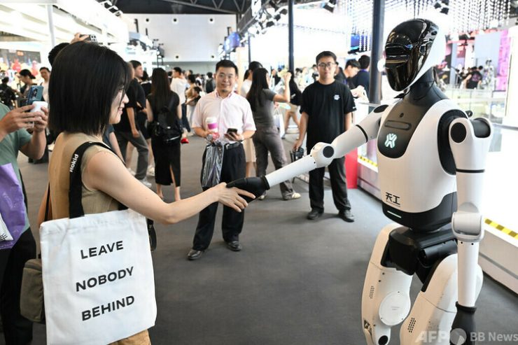 上海で開催された世界人工知能大会にて人型ロボットと来場者が握手する様子=2025年7月26日撮影・飼料写真(c)CNS:田雨昊