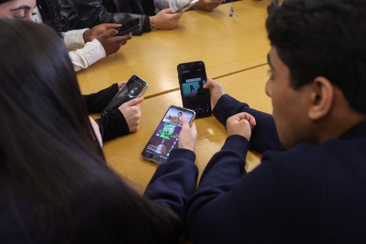 写真は携帯電話を見る学生ら。ウィンブルドンで2月撮影。REUTERS/Katie Collins