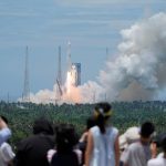 2026年7月10日、中国・海南省の文昌宇宙船発射場から「長征10B」ロケットが打ち上げられ、その後、制御された回収のため沖合のプラットフォームへ垂直に帰還する様子を、人々が眺めている。中国日報（REUTERS経由）