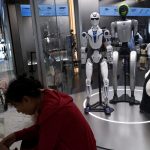資料写真：2026年8月10日、中国・北京のユニツリー店舗で展示されているユニツリーのヒューマノイドロボットG1とR1の近くで休憩する人々。ロイター/王廷舒/資料写真