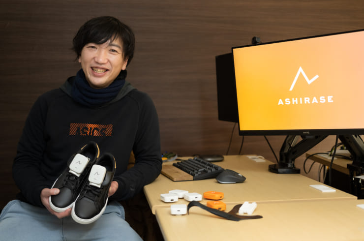 視覚障がい者向け歩行ナビゲーションシステム「あしらせ」を装着した靴を手に持つ株式会社Ashirase代表取締役CEO 千野歩（ちの・わたる）氏