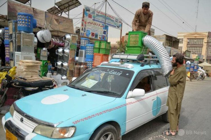 アフガニスタンのカンダハルの市場で、タクシーの屋根に冷風扇システムを取り付ける運転手（2025年7月8日撮影）。（c）Sanaullah SEIAM:AFP