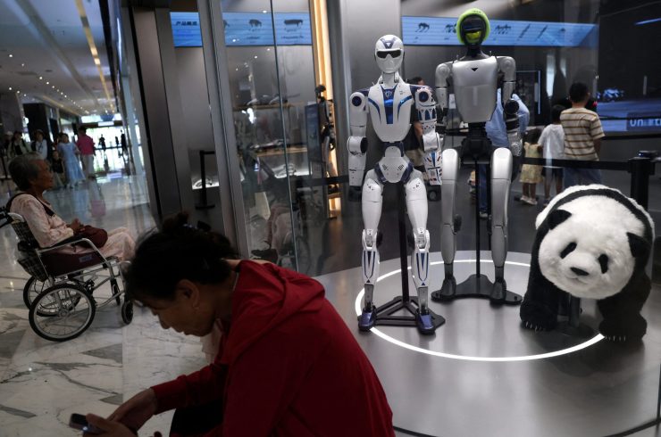 資料写真：2026年8月10日、中国・北京のユニツリー店舗で展示されているユニツリーのヒューマノイドロボットG1とR1の近くで休憩する人々。ロイター/王廷舒/資料写真